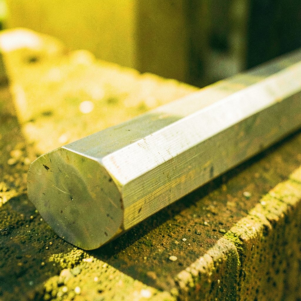 AISI 5140 alloy steel bar stock in square profile, dark gray with subtle mill scale finish